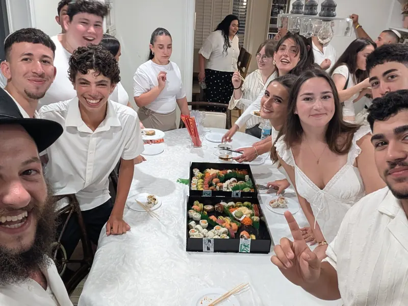 Teens and Rabbi Yosef around a Shabbat dinner table